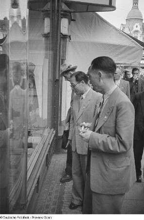 Asiatische Messegäste vor einem Fotogeschäft in der Innenstadt
