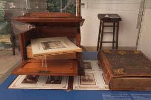 Dresden. SLUB. Ausstellung "Geteilte Erinnerungen. Das Fotoalbum - gesteckt, geklebt, gepostet" im Buchmuseum. Hochvitrine "Prachtalben". Teilansicht mit hölzerner Schatulle für fotografische Serie der Altenburger Feuerwehr und Album für Generaldirektor Wilhelm Bär zum 80. Geburtstag
