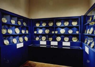 Raumaufnahme. Ausstellungsraum Das herzogliche Urbino und die Istoriato-Malerei". Ansicht mit Vitrinenschränken mit Tellern