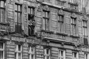 Zwei junge Männer am Fenster eines Wohnhauses