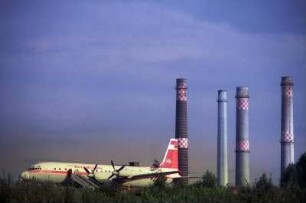 Iljuschin 18 in Harbke, dahinter die Schlote des Kohle-Kraftwerks. Im Flugzeug befinden sich ein Stadesamt, sowie ein Café. 1994