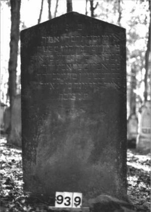 Grabstein 939 (Index: 99899447) Material: Sandstein Zustand: leicht verwittert Maße HxBxT: 125x66x8 cm Beschreibung: Stele mit Dreiecksabschluss Besonderheit: kulturhistorisch wertvoll / hist.-wiss. Gründe (Gemeindestellung): Grabstein 939