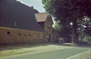 Hohenfelde 6: Gasthof Stahmer: traufständige Straßenfront mit Zwerchgiebel über Eingangstür, Gaststättenschild, Postkasten, Zigarettenautomat: davor Baum, Straße