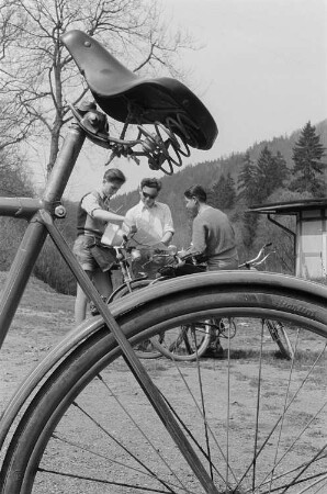 Drei junge Radfahrer studieren die Landkarte, im Vordergrund ein Rad des Reifenherstellers Barum