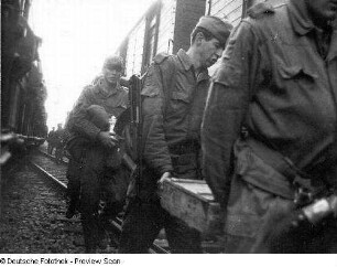 Deutschland . Truppenübungsplatz Klietz. Nationale Volksarmee - Landstreitkräfte. Truppenverlegung per Eisenbahnmarsch. Soldaten mit Munitionskiste (?) zwischen zwei Militärzügen