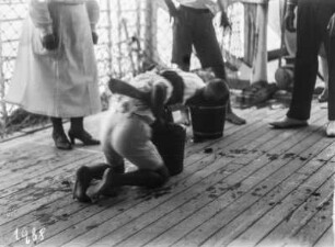 Freitzeitbeschäftigung : Männer beim "Apfel fischen" an Deck eines Schiffes