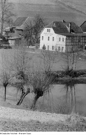 Das Gasthaus "Zur fröhlichen Einkehr" und weitere Häuser, im Vordergrund Ein Gewässer