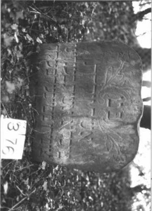 Grabstein 376 (Index: 99898357) Material: Sandstein Zustand: angewittert, eingesunken Maße HxBxT: 59x58x9 cm Beschreibung: Stele mit geschweiftem Flachbogenabschluss, im Bogenfeld eingeritzte Blumenranken, eingesunken Symbolik: Blumen: Grabstein 376