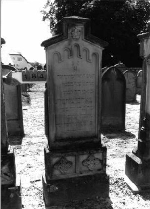 Grabstein 184 (Index: 99797616) Material: Sandstein, weiß Zustand: leicht verwittert Maße HxBxT: 193x66x20 cm Beschreibung: Stele, Giebel rechteckig erhöht, getreppter Sockel Symbolik: Blüten, Rundbogenfries: Grabstein 184