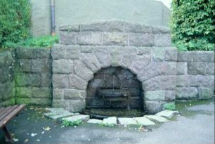 kleiner Laufbrunnen in einer Natursteinmauer unterhalb der Bergkirche