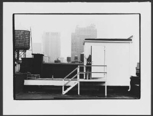 Rooftop : New Yorker Dach mit Zisterne und Ausblick auf Hochhäuser, ein Mann eine Tür öffnend