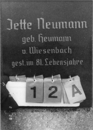 Grabstein 12 (Index: 100114971) Material: ? und polierter Granit Zustand: gut Maße HxBxT: 180x55x18 cm Beschreibung: Stele auf Sockel, überstehender Spitzgiebel mit Stern, eingesetzte Textplatte: Grabstein 12A