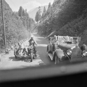 Straßenszene in den Alpen mit Auto und Motorrad mit Beiwagen