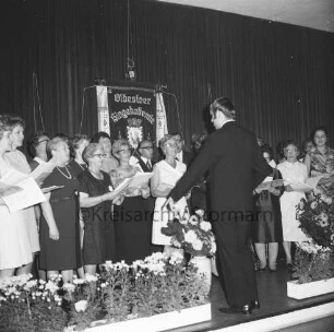 Oldesloer Singakademie von 1946: Oldesloer Hof: Saal: Festveranstaltung zum 25-jährigen Jubiläum: Gesangsvortrag des Chores: rechts Chorleiter: hinten Fahne: vorn Blumenschmuck: 26.09.1971