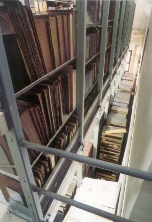 Sächsische Landesbibliothek - Staats- und Universitätsbibliothek Dresden. Zentralbibliothek (ehem. Landesbibliothek). Erdgeschoss (Flachbau). Abteilung Benutzung, Magazin. Blick vom aufgeständerten Zwischenboden nach unten auf gestapelte Bestände : Dresden-Neustadt, Marienallee 12. Sächsische Landesbibliothek - Staats- und Universitätsbibliothek Dresden. Zentralbibliothek (ehem. Landesbibliothek). Erdgeschoss (Flachbau). Abteilung Benutzung, Magazin. Blick vom aufgeständerten Zwischenboden nach unten auf gestapelte Bestände