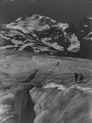 Auf dem Gletscher : Blick über das gerissene Eis auf den Morteratschgletscher und Bergsteiger. Im Hintergrund ist der Piz Bernina erkennbar.
