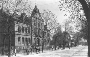 Cossebaude (Dresden-Cossebaude), Bahnhofstraße 5. Schule (1893). Straßenansicht mit Einfriedung und Schulkindern