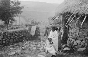 Steinhütte der Amhara : Frau und Mann auf einem von einer Steinmauer umgebenen Hof, neben ihnen eine Steinhütte.