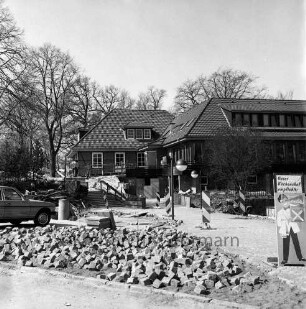 A 1: Raststätte "Trave" bei Reinfeld: Modernisierung: Pflasterung des Außengeländes, Pflastersteine, Betonplatten, Warnbaken: parkendes Auto: hinten Gaststättengebäude, Personen auf Terrasse: vorne rechts Hinweisschild "Unser Küchenchef empfiehlt"