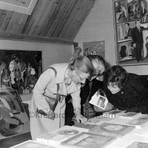 Rade: Museum Rade im Naturpark Oberalster: Ausstellung "Europas Sonntagsmaler": vorn drei Besucherinnen an Tisch mit Katalogen