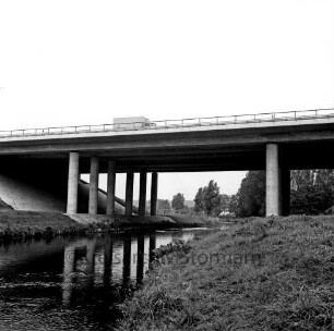 A 1: bei Reinfeld: Travebrücke bei Autobahnraststätte "Trave": Seitenansicht: Trave, mit Spiegelung der Betonpfeiler: oben auf Brücke Lkw