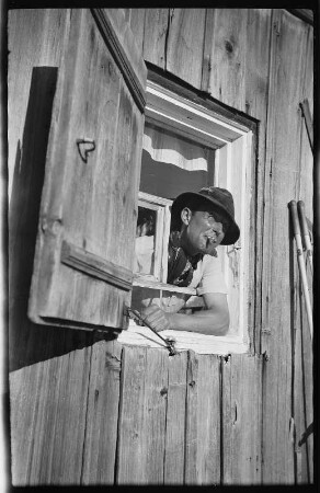 Mann aus dem Fenster eines Holzhauses blickend