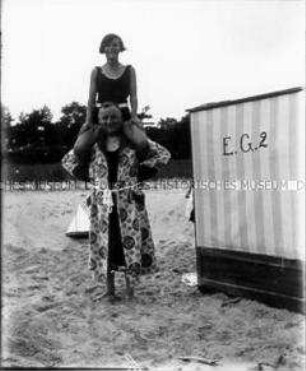 Mann und Mädchen im Huckepack am Strand