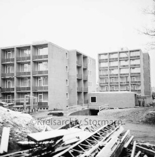 LVA-Krankenhaus Großhansdorf der Landesversicherungsanstalt Hamburg [später: LungenClinic Grosshansdorf]: Wöhrendamm: Neubau: zwei Wohnblocks für Personal nach Fertigstellung: vorn Gerüstteile und Baumaterial: hinten rechts zwei Personen