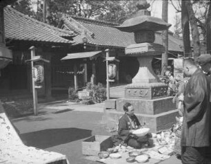 Tempelfest im Ikegami Honmon-ji. Geschirrverkäufer neben einer Steinlaterne : Tokyo-Omori (heute Tokyo-Ōta). Tempelfest im Ikegami Honmon-ji. Geschirrverkäufer neben einer Steinlaterne