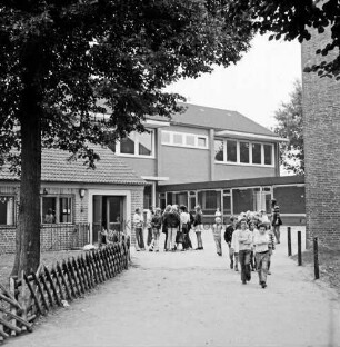 Grundschule: Soltausredder: altes Schulgebäude mit mehreren Erweiterungsbauten: links Zaun, dahinter Baum: rechts hinten Schulkinder