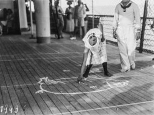 Frau beim Malen : Eine Frau zeichnet mit Kreide ein Schwein auf das Deck eines Schiffes