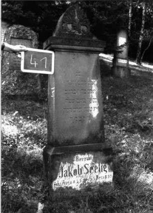 Grabstein 41 (Index: 100101035) Material: Sandstein Zustand: verwittert Maße HxBxT: 157x41x18 cm Beschreibung: Stele, Sockel, Abdeckplatte mit Palmettenaufsatz Symbolik: Palmette Besonderheit: eingemeißelte Nummer: 28: Grabstein 41