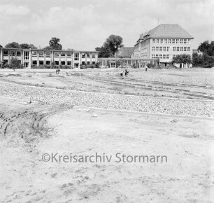Sportplatz: Bargenkoppelredder: von Gymnasium Stormarnschule, Waldstraße: in Bau: Arbeiter beim Legen des Unterbaus für Spielfeld und Leichtathletikbahn: im Hintergrund Stormarnschule mit verschiedenen Bauphasen