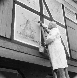 Herborn-Seelbach. Walzenmühle. Mann beim Malen einer Windmühle auf die Hauswand