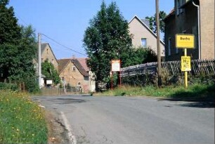 Straße mit Ortseingangsschild; Häuser