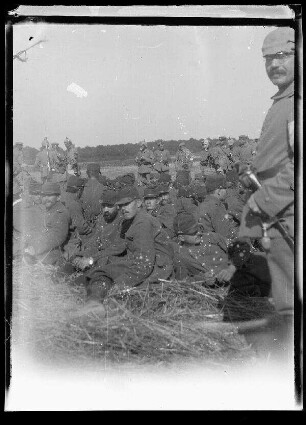 Unbekannte Gegend [Nordfrankreich?]: Soldaten mit Feldmützen (französische Gefangene?) im Kauern am Boden, davor und dahinter Soldaten mit Pickelhaube und Offiziere und Soldaten mit Schirmmütze und Pickelhaube