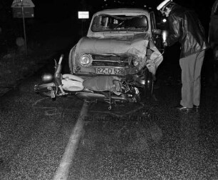 Verkehrsunfall: Industriestraße, bei Einmündung in B 208 / Ratzeburger Straße: Zusammenstoß von Pkw mit Kleinmotorrad: Unfallwagen Renault R4 mit eingedrückter Front, davor quer am Boden Kleinmotorrad: Polizist, auf Straße Markierungen der Polizei: hinten Verkehrszeichen, Ortsschild: im Dunkeln