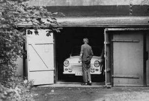 Mann vor einem in einer Garage stehenden PKW "Trabant"