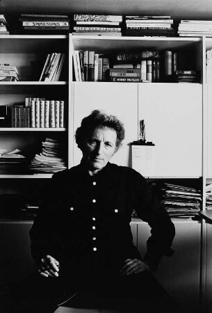 Der Schriftsteller Paul Wiens in seinem Arbeitszimmer vor einem Bücherregal sitzend
