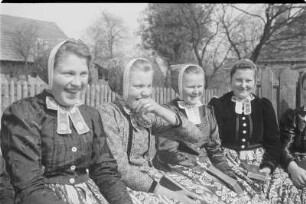 Mädchen in Schleifer Tracht aus Rohne auf der Singebank in Rohne. : Holcy w Slepjanskej drasće z Rowneho na spěwarskej ławcy w Rownom.
