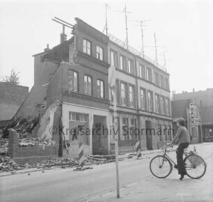 Hagenstraße: Abriss des Hauses Nr. 47: links teilweise abgebrochene Mauern: vorn rechts Junge auf Fahrrad: hinten rechts Firmenschild der Volksbank Bad Oldesloe: 15. Mai 1975