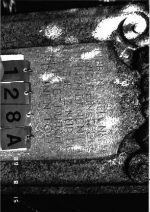 Grabstein 128 (Index: 100105327) Material: Granit Zustand: verwittert und gebrochen Maße HxBxT: 177x67x23 cm Beschreibung: Stele, Rundbogenabschluß nach unten in Voluten auslaufend, erhabenes Schriftfeld Symbolik: Voluten, Blattwerk über Schriftfeld: Grabstein 128A