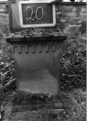 Grabstein 20 (Index: 100080696) Material: Sandstein Zustand: stark verwittert mit Textverlust Maße HxBxT: 64x32x20 cm Beschreibung: obeliskartiger Abschluß, Stele Symbolik: gestelztes Rundbogenfries: Grabstein 20