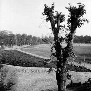 Stormarnhalle: Außenanlage vorne, dahinter Grünfläche und Sportplatz am Exer, links der Konrad-Adenauer-Ring: Blick nach Westen