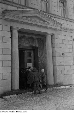 Gruppe in einen Neubau der Stalinallee (heutige Karl-Marx-Allee) gehend