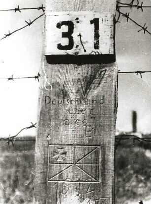 Pfosten vom elektrischen Zaun eines faschistischen Konzentrationslagers mit der Aufschrift "Deutschland über alles"