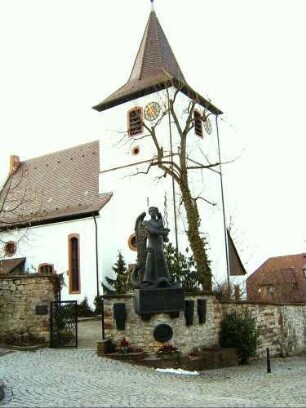 Ansicht von Südosten mit Kirche (Chorturm mit Schlitzscharten sowie einst festem Langhaus) über Kirchhofmauer
