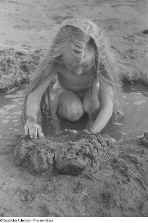 Mädchen, an einem Ufer mit Sand spielend