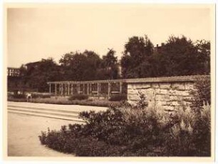 Grünanlage mit Spielplatz, Hindenburg: Bepflanzung an der Natursteinmauer, dahinter Laubengang