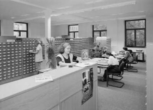Deutsche Fotothek (Loge; heute SLUB Dresden / Deutsche Fotothek). Auskunfts- u. Benutzungsraum, Teilansicht mit Katalogen und Benutzerplätzen, Mitarbeiterin Bettina Erlenkamp an der Auskunftstheke